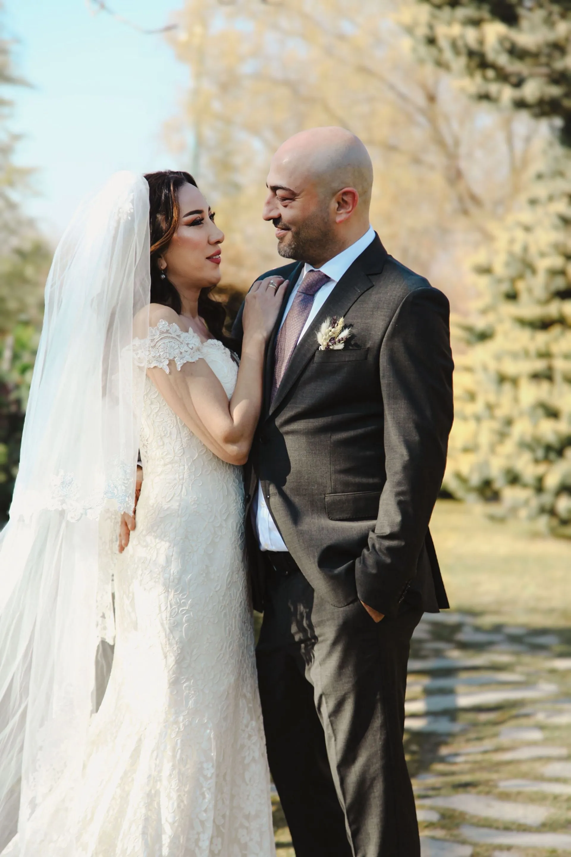 Ormanlık bir alanda, altın ışıkta birbirine sarılan gelin ve damadın dışavurumcu portresi.