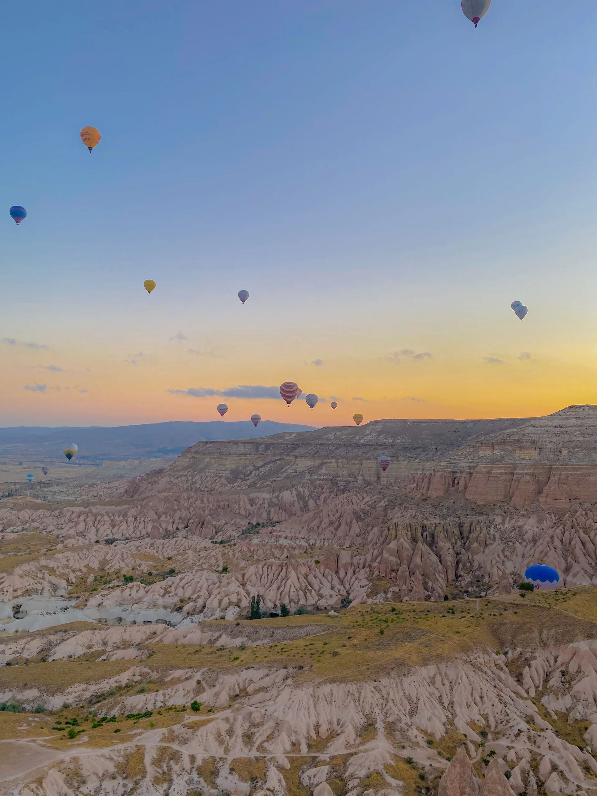 Kapadokya'nın peri bacaları üzerinde gün doğumunda süzülen onlarca sıcak hava balonu.